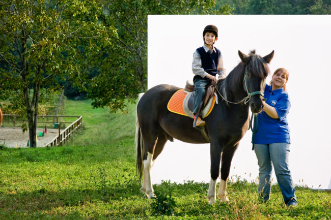 Volontaria con bambino e cavallo