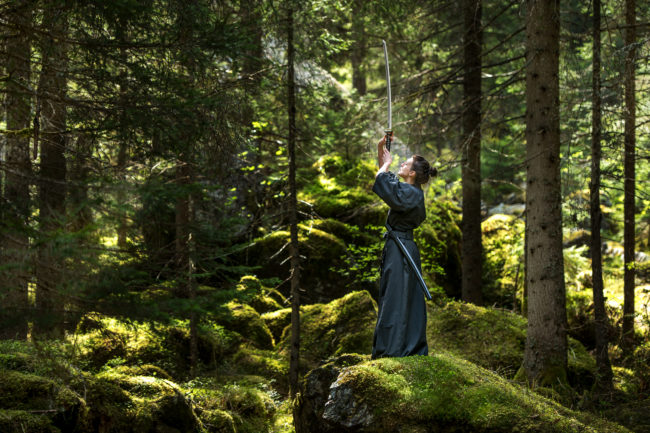 un'atleta si esercita con la katana in un bosco