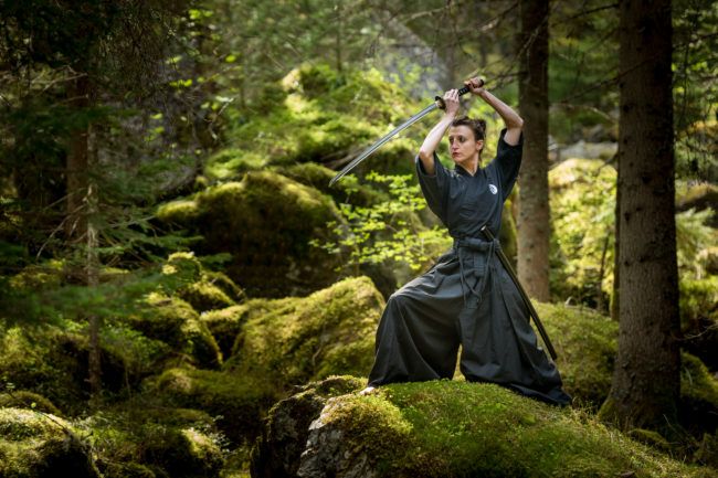 un'atleta si esercita con la katana in un bosco