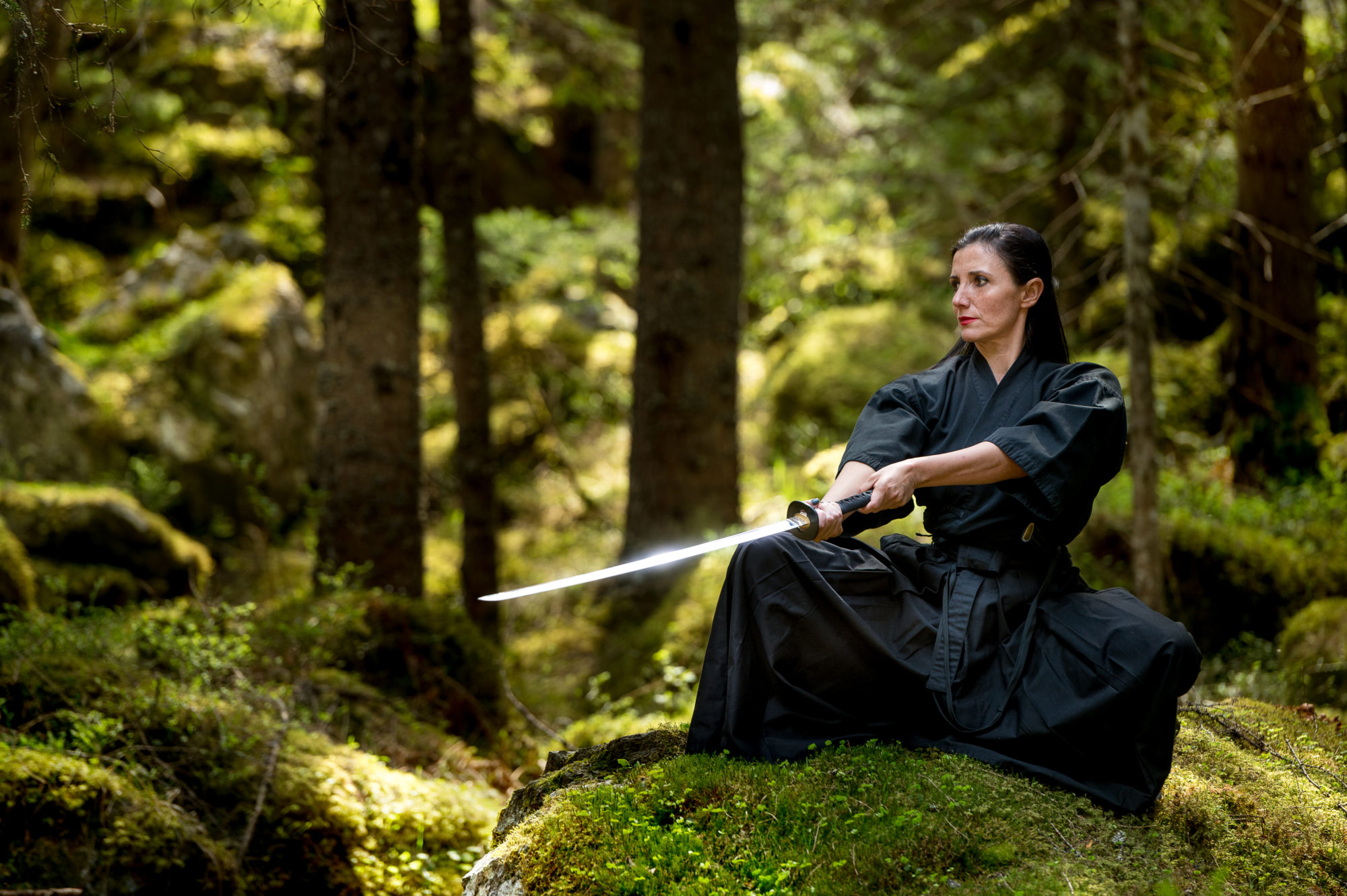 Foto di un’atleta si esercita con la katana in un bosco