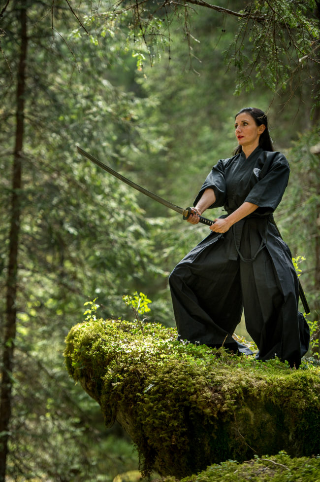 donna pratica Yoga con la katana in mezzo alla natura