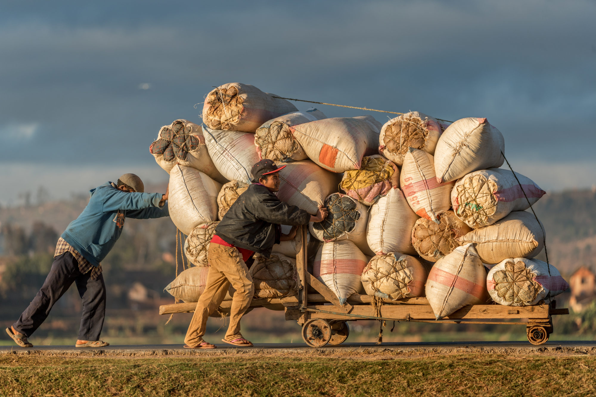Foto di due uomini trascinano un carretto carico di merci