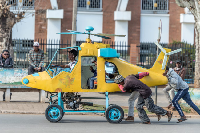 bambino su un elicottero giocattolo trascinato da degli uomini