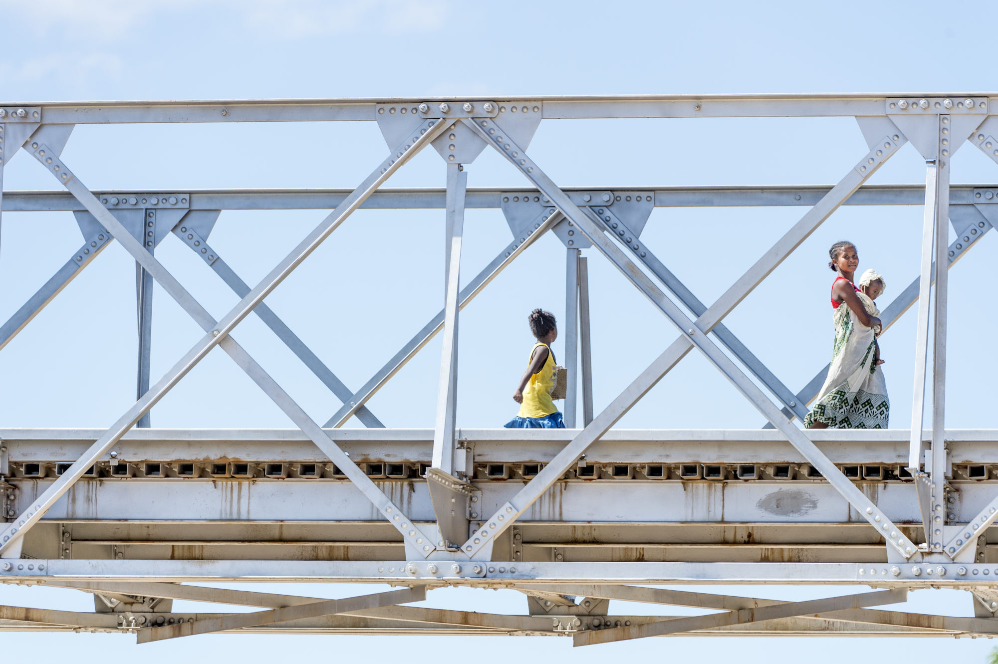 Foto di una donna e due bimbe percorrono un ponte