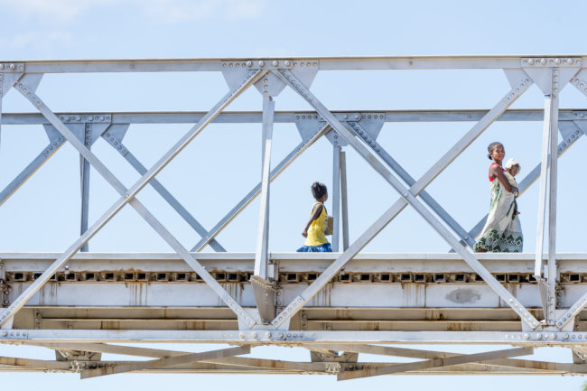 una donna e due bimbe percorrono un ponte