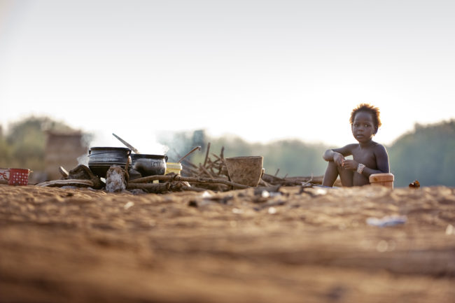 Bambina nomade che mangia su una spiaggia sul fiume Niger