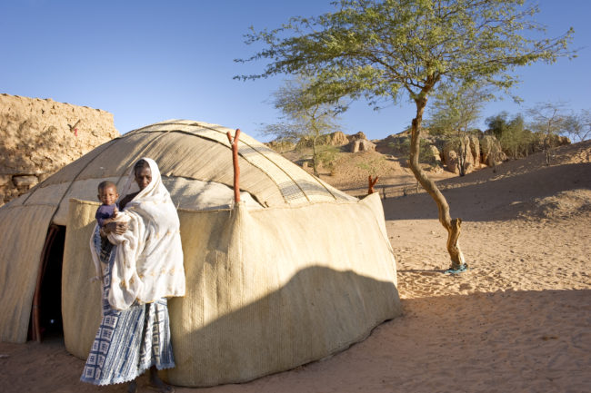 Donna con il suo bimbo fuori dalla propria tenda in un villaggio