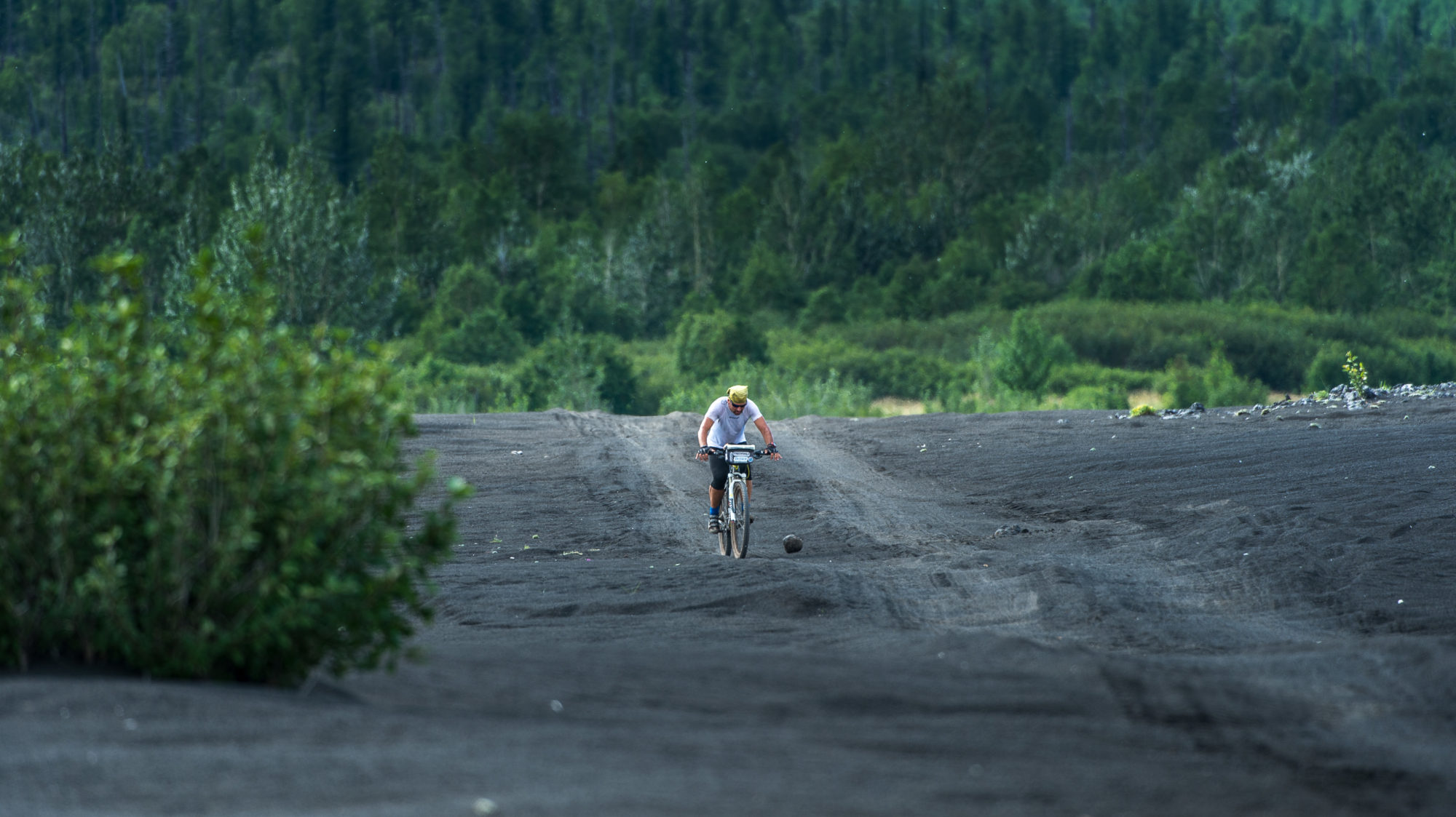 Foto di aldo mazzocchi esce dalla foresta e pedala verso il campo alla base del vulcano tolbachik