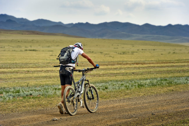 Ciclista che spinge la bici sul percorso della Mongolia Bike Challange