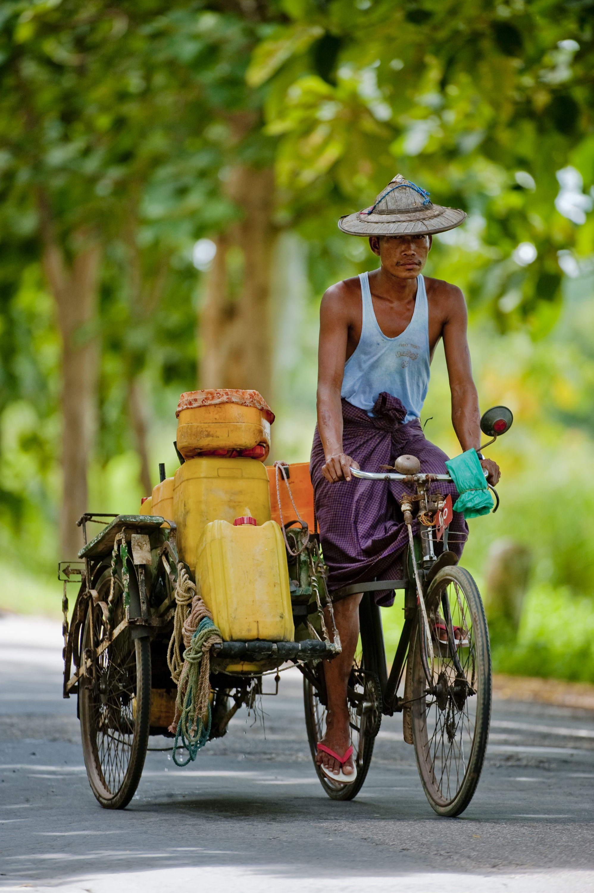 Foto di Uomo trasporta taniche in bicicletta su una strada in Myanmar