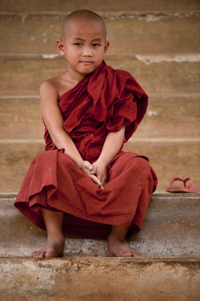 Giovane monaco buddista sulle scale di un tempio in Myanmar