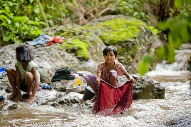 Bambine che lavano i panni in un fiume in Myanmar