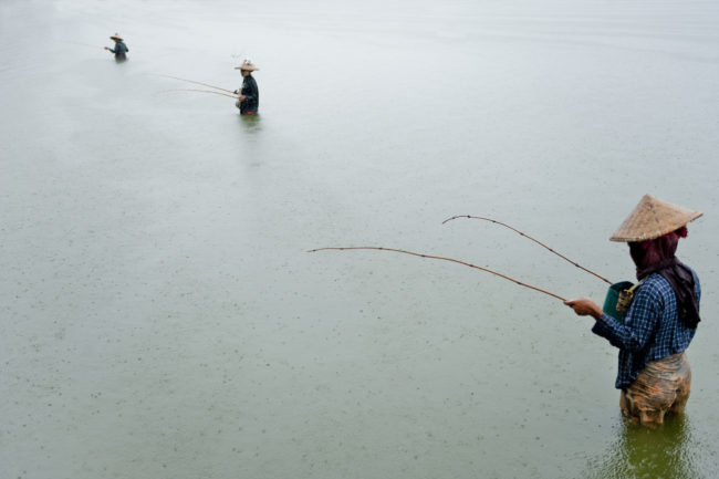 Pescatori al lavoro sul lago Inle in Birmania sotto la pioggia