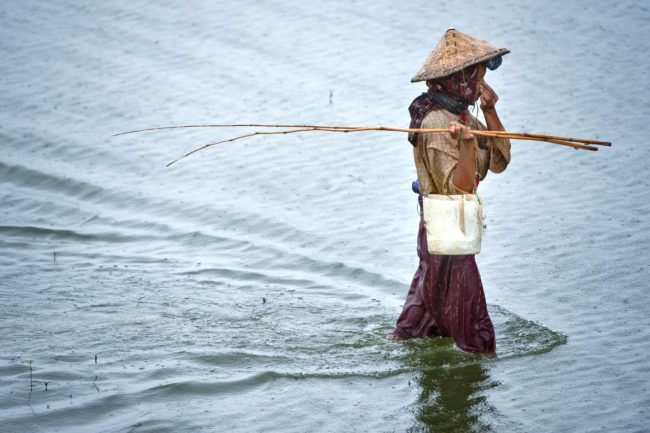 Pescatore al lavoro sul lago Inle in Myanmar sotto la pioggia