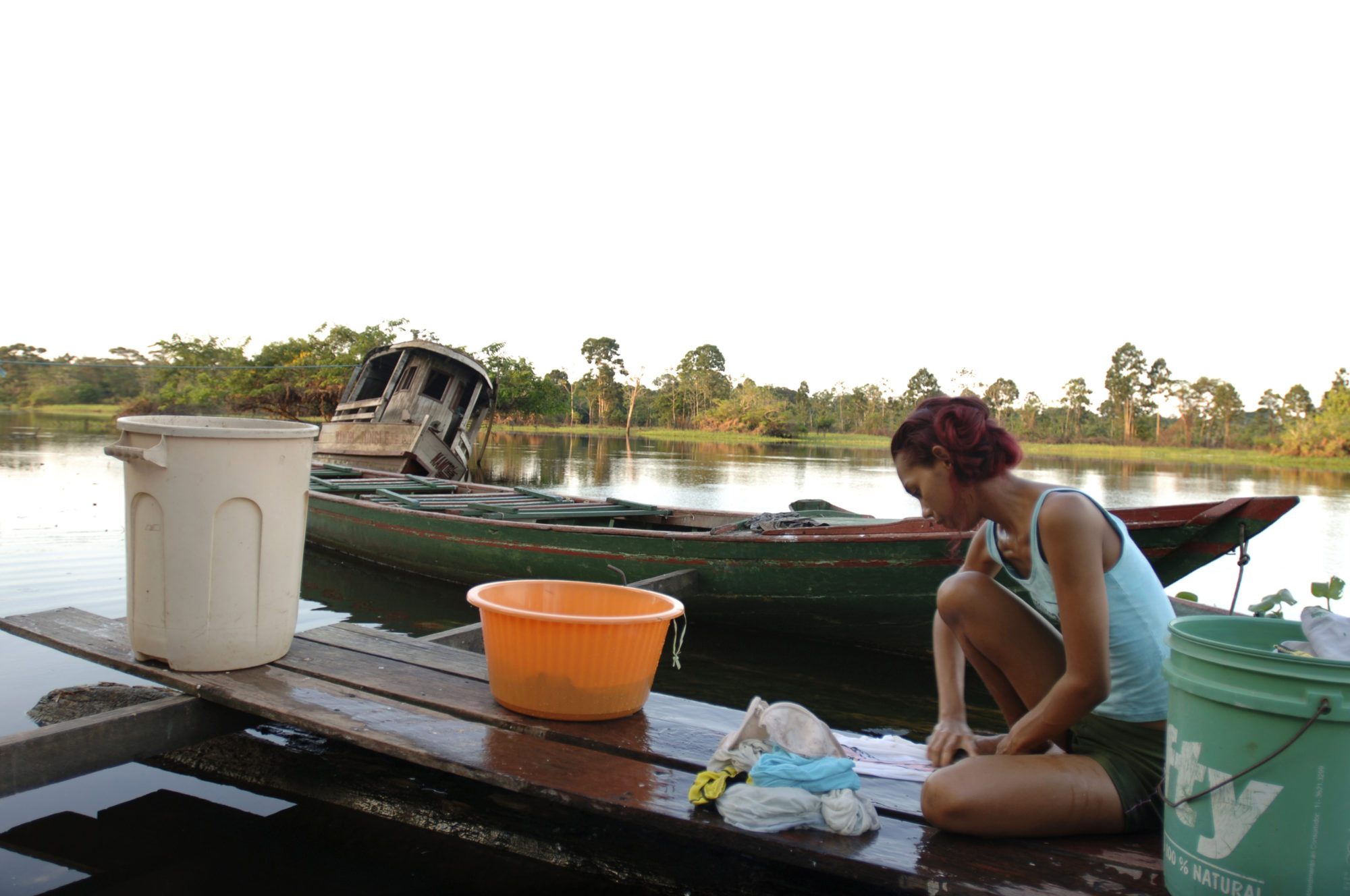 Foto di ragazza lava i panni in riva ad un fiume amazzonico