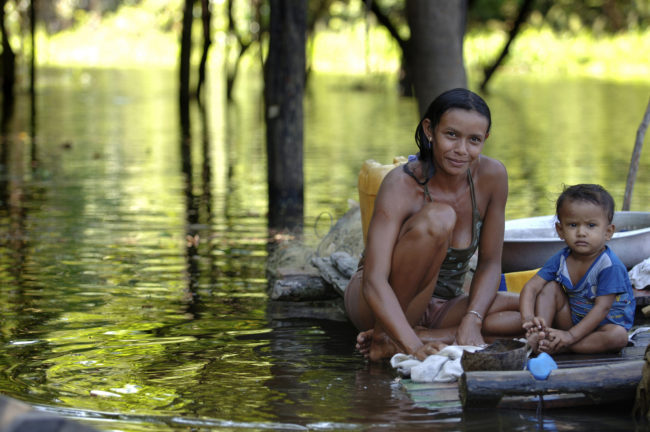 donna con bambino che lava i panni in un fiume amazzonico