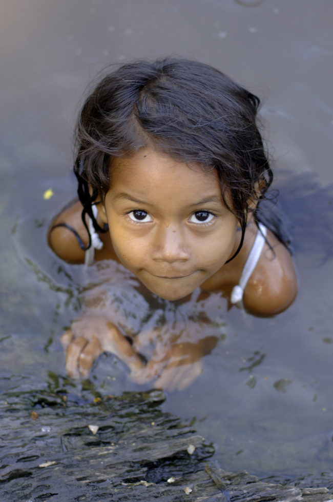 bambina gioca nell'acqua di un fiume amazzonico