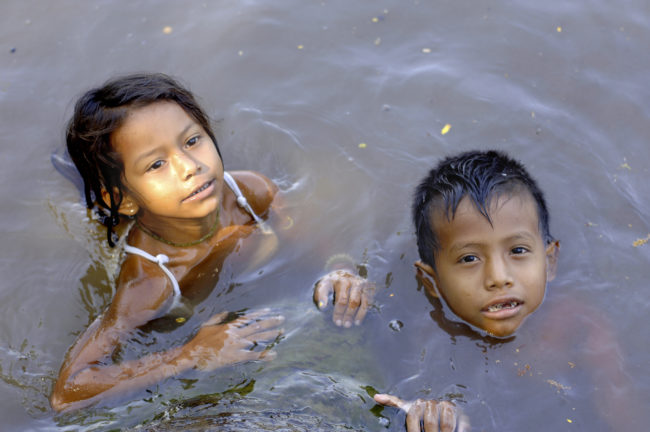 bambini giocano nell'acqua di un fiume amazzonico