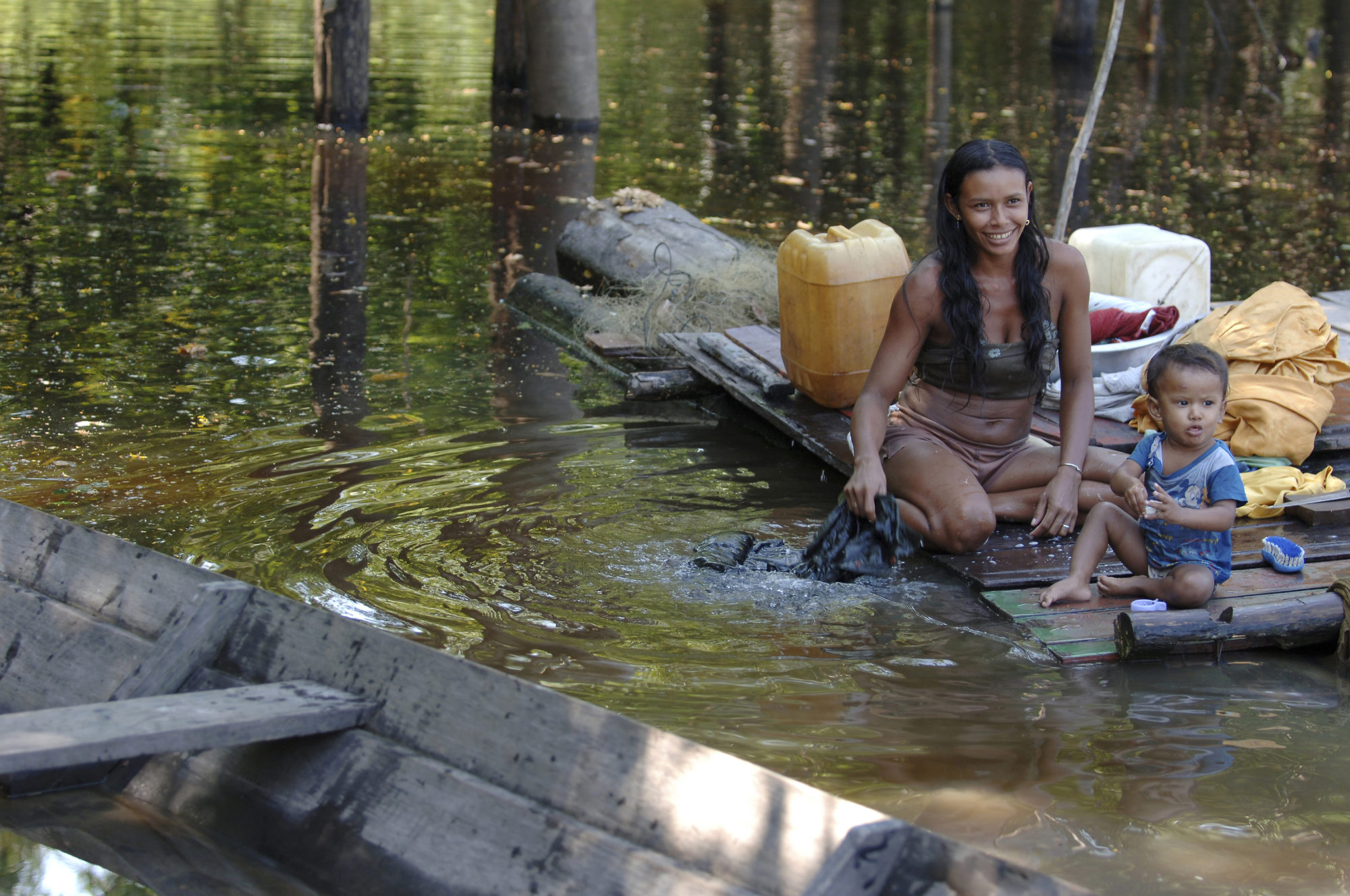 Foto di donna con bambino che lava i panni in un fiume amazzonico