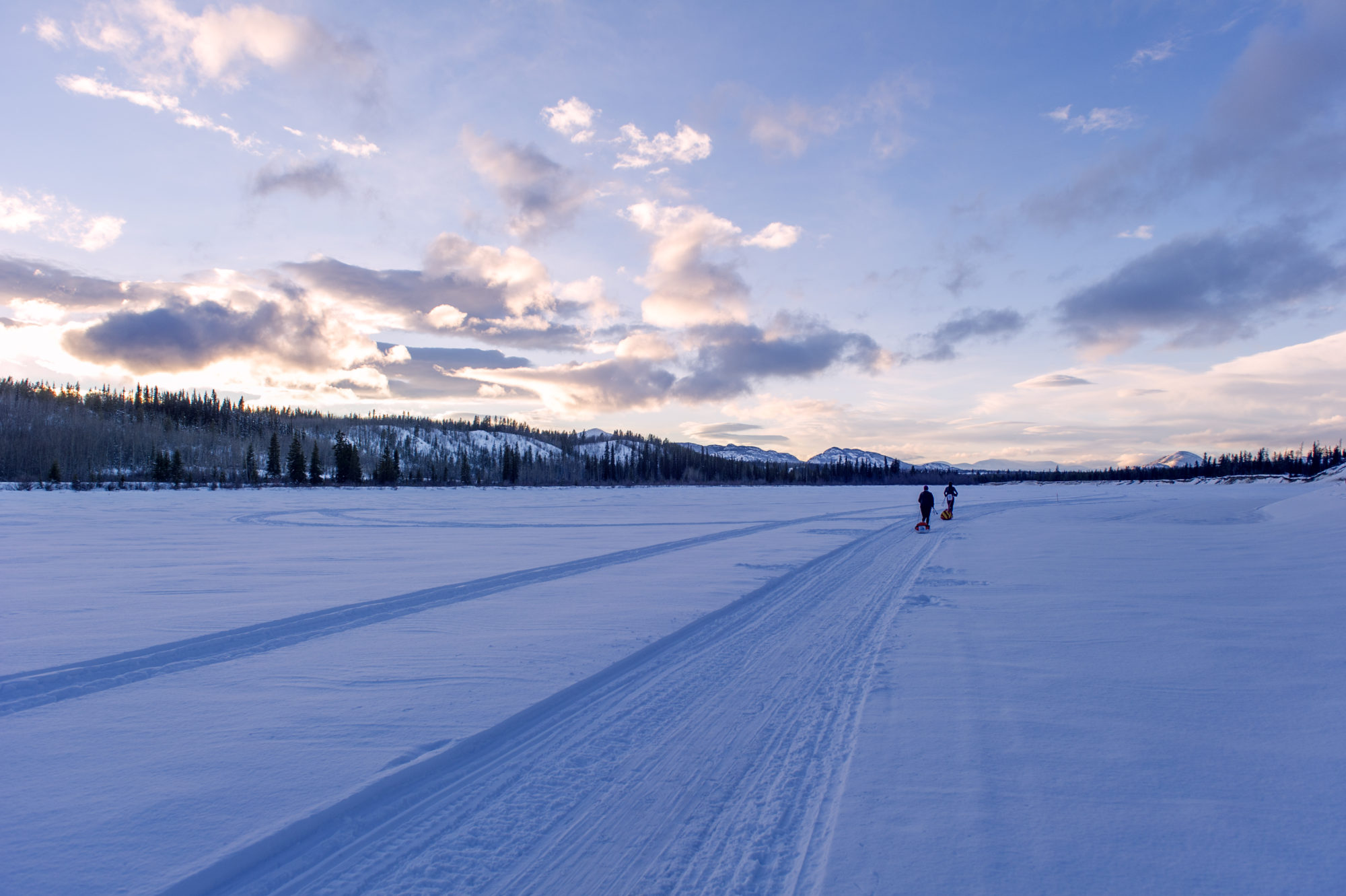 Foto di due partecipanti alla yukon arctic ultra camminano al tramonto