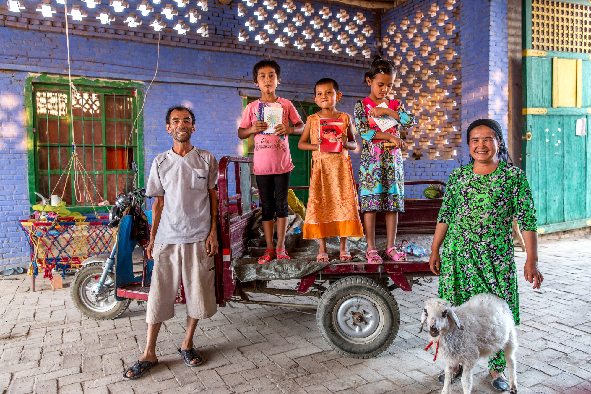 Foto di Turpan: una famiglia e la loro pecora all’interno di un cortile