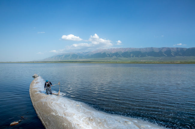 Lago Qinghai. Un uomo fa una diga con delle bottiglie vuote