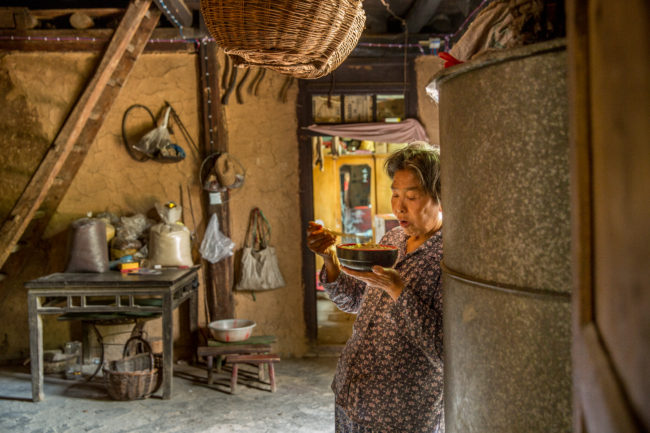 Una donna consuma il pranzo in piedi nella sua casa