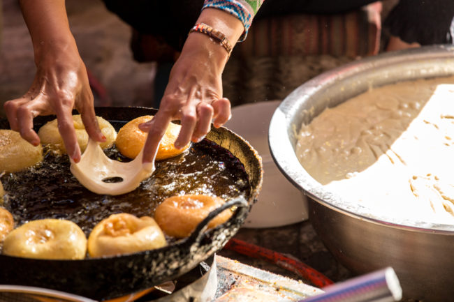 Una donna cucina frittelle al mercato di Kashgar