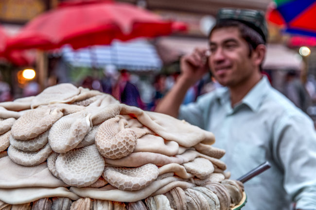 Un uomo vende cibo al mercato di Kashgar