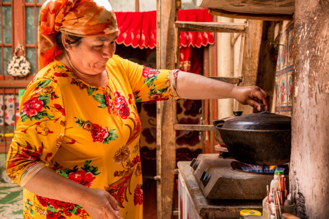 Una donna cucina all'interno di un cortile a Kashgar