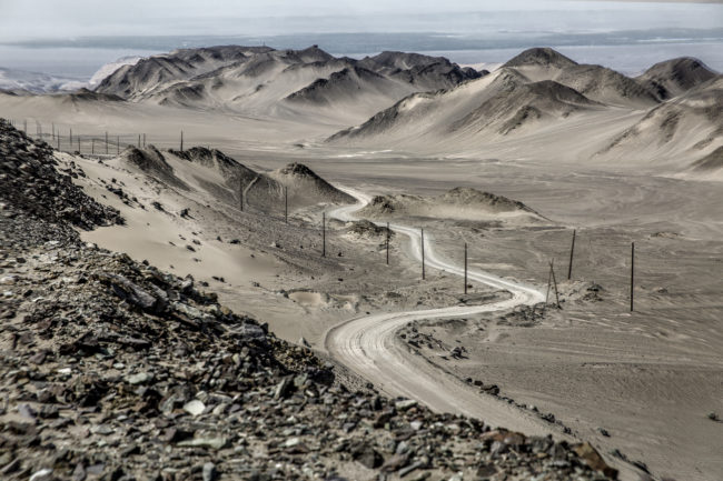 Una strada corre ai margini del deserto del Taklamakan
