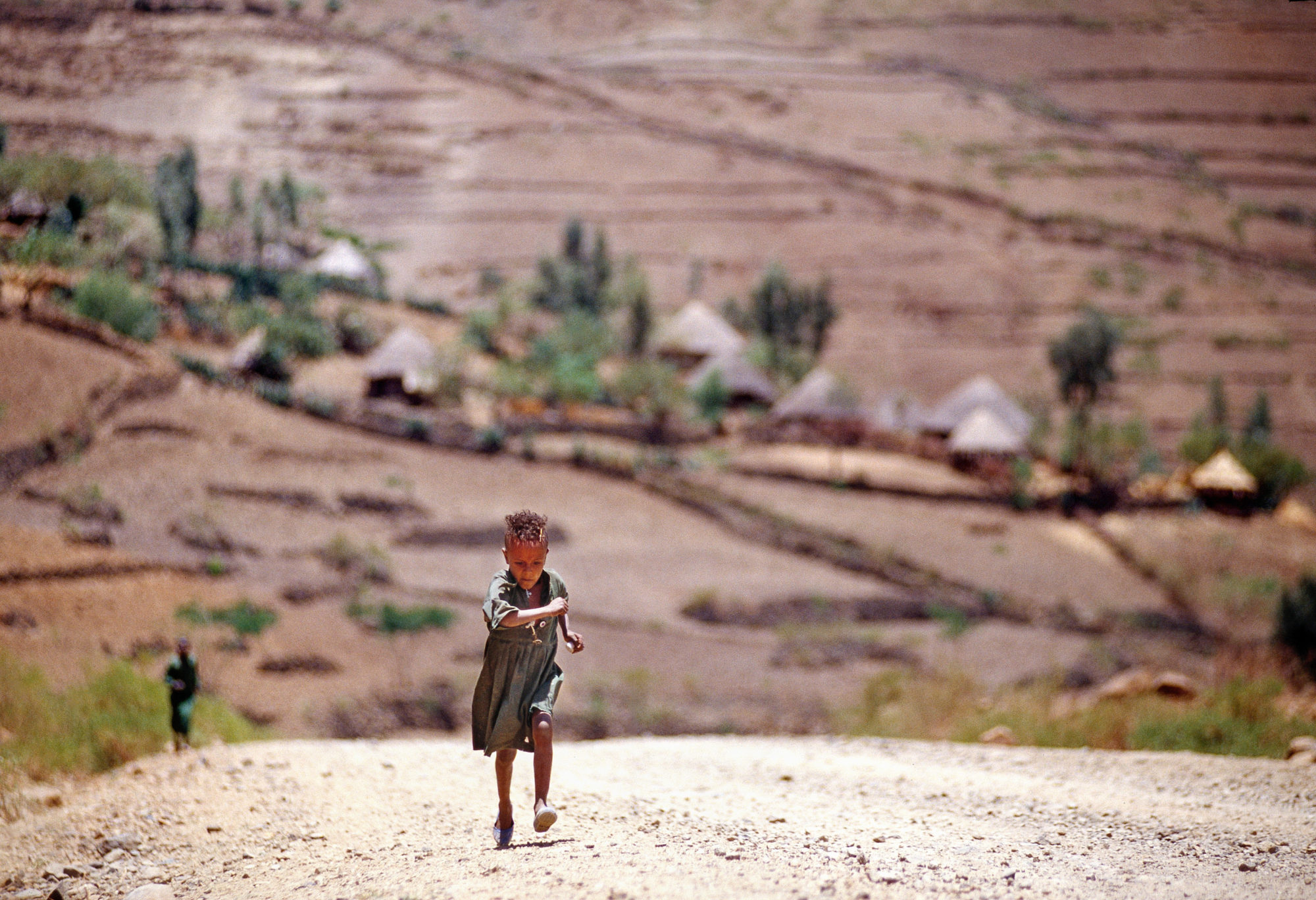 Foto di Bambina che corre su strada sterrata