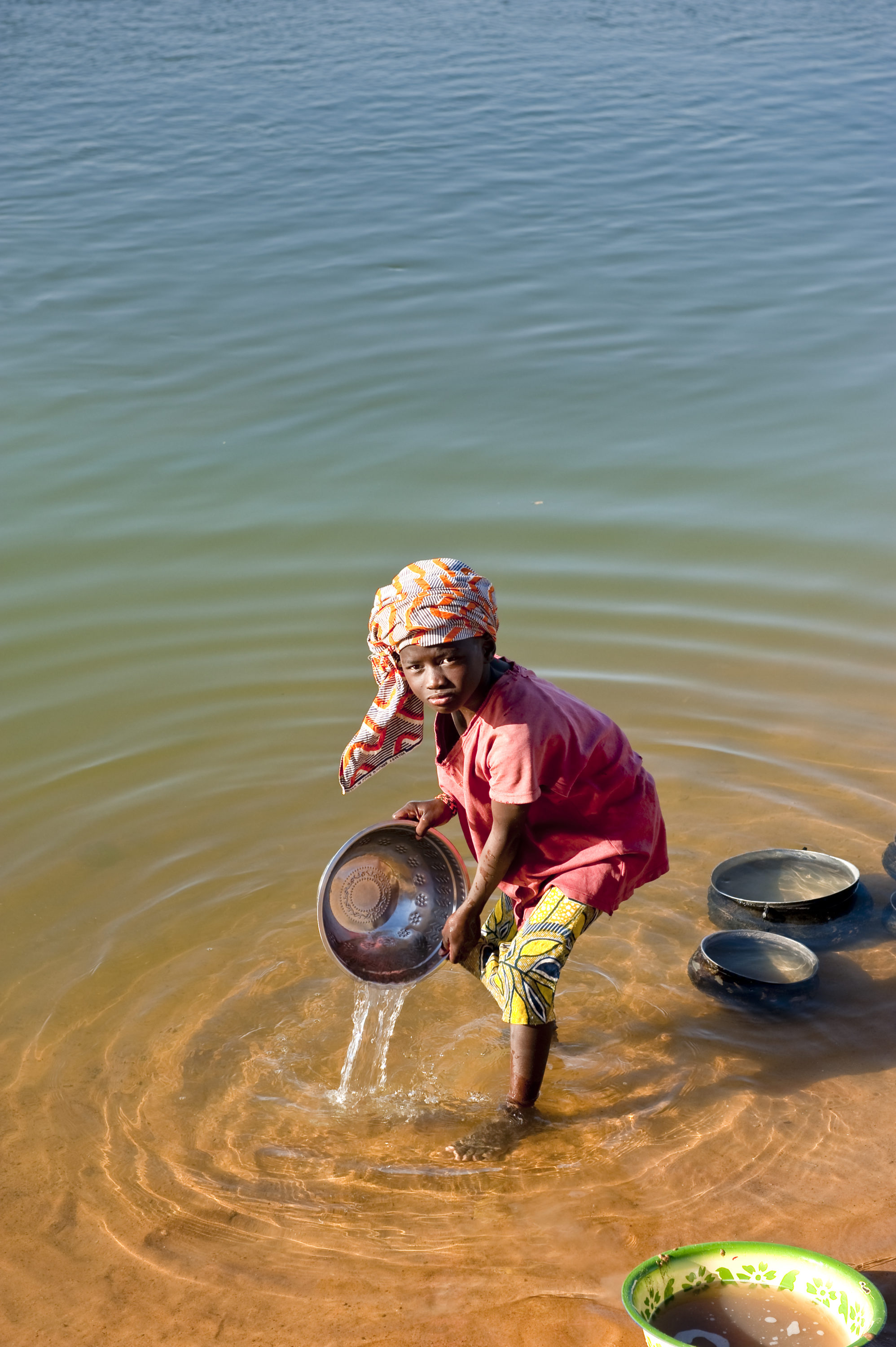 Foto di Bambina che lava le stoviglie sul fiume Niger