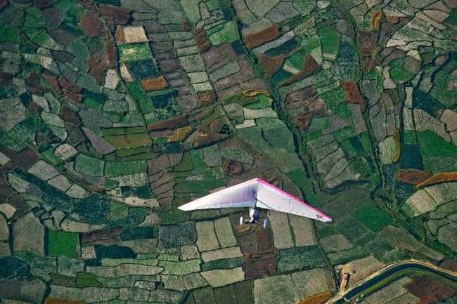 Deltaplano che vola sopra terreni agricoli