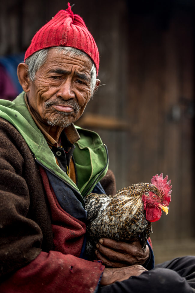 un uomo col suo gallo davanti alla sua casa nel tamang heritage